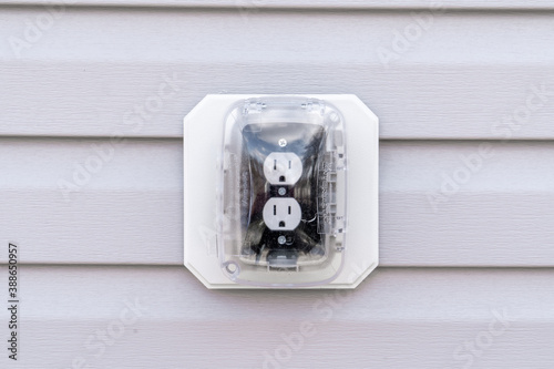 Closeup view of black socket white double outlet with plastic cover on a house