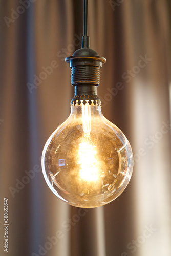 round incandescent lamp hanging on brown blurred background © avrezn