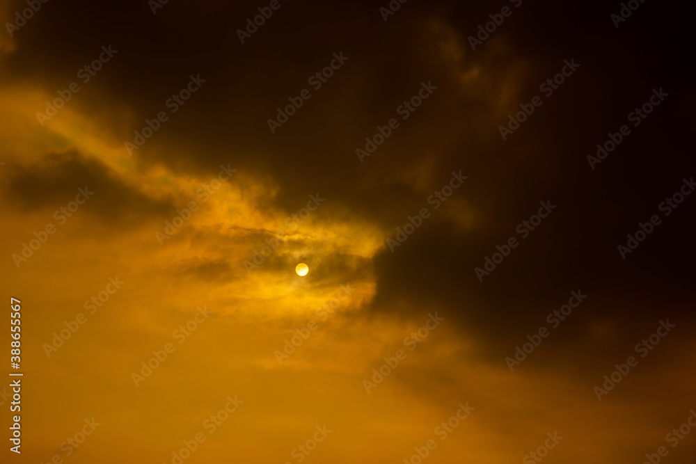 Dark cloud on orange sky background, saw little shape of the sun
