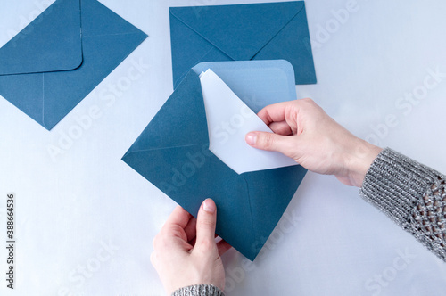 A woman's hand takes a letter from an open blue envelope isolated on a white background