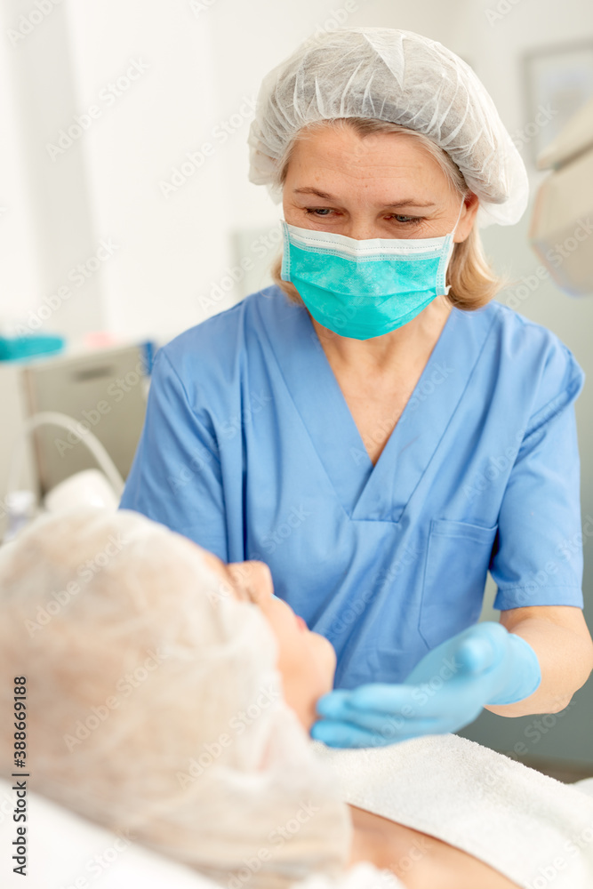 Fototapeta premium Professional cosmetician examining face skin of girl in clinic of esthetic cosmetology. High quality photo