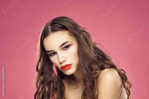 Attractive woman fashionable hairstyle bared shoulders and red lips pink background