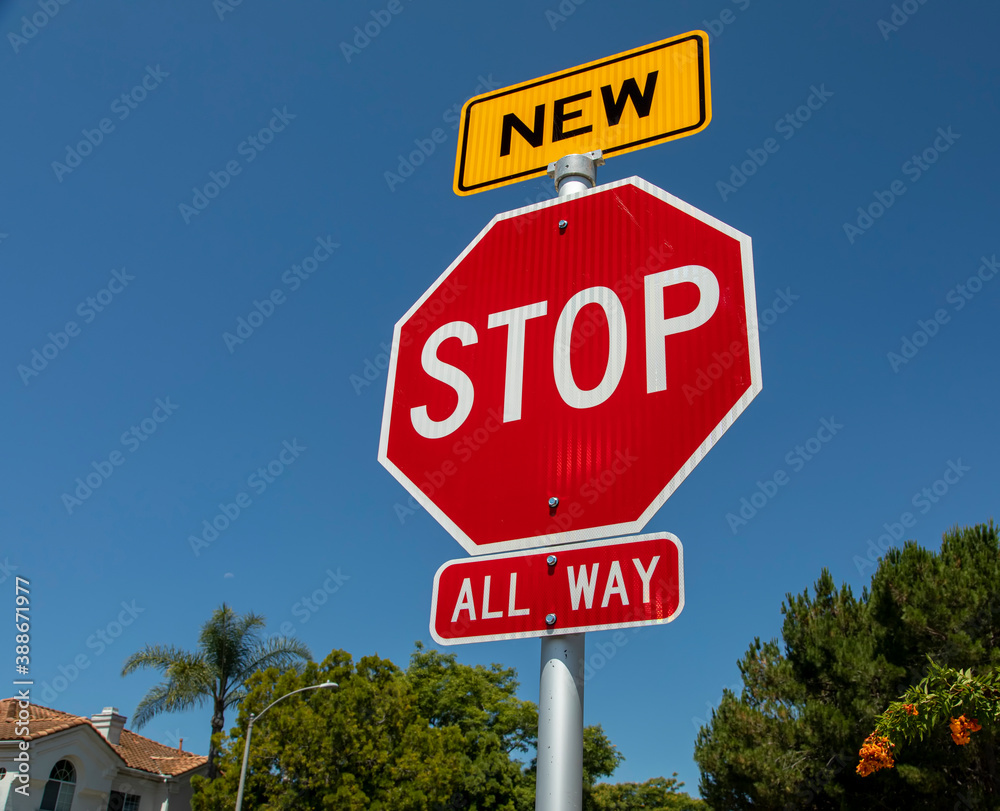A recently installed stop sign with a small sign in yellow with the word New on top of the stop sign A recently installed stop sign with a small sign in yellow with the word New on top of the stop sign