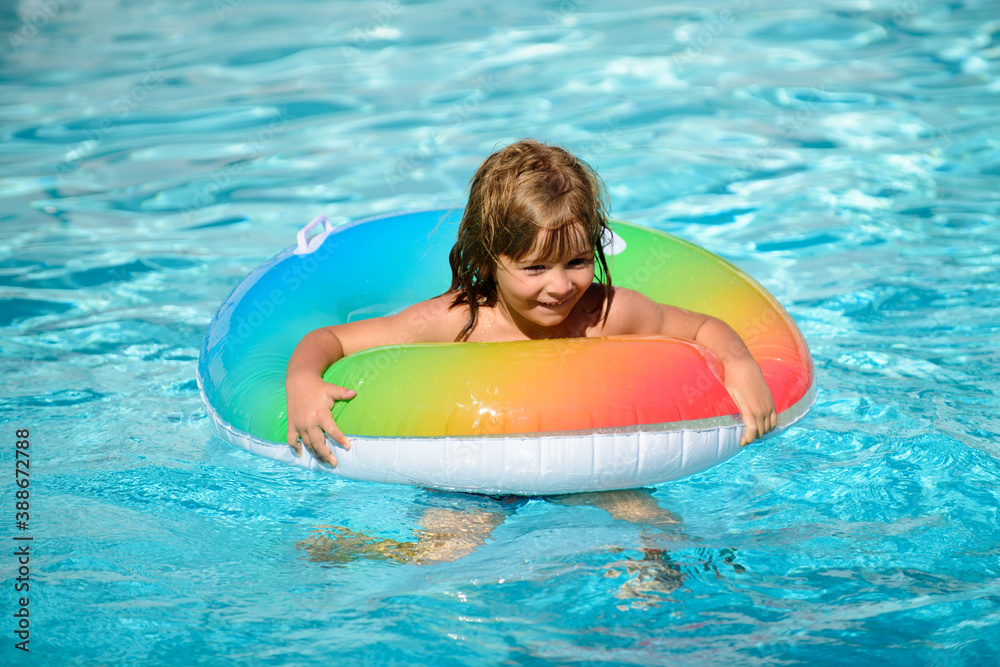 Child in swimming pool playing in water. Vacation and traveling with kids. Children play outdoors in summer. Kid with floating ring.