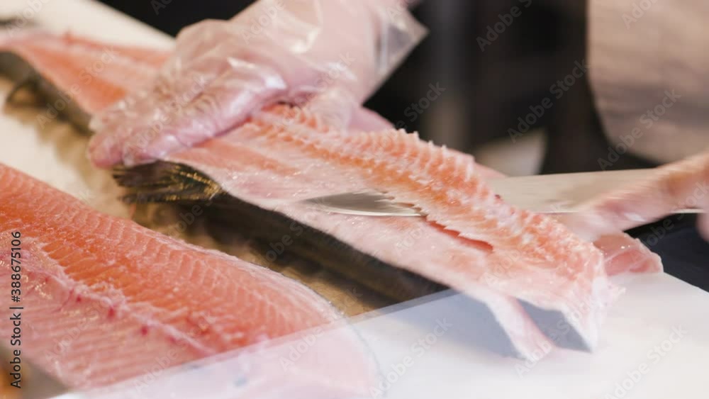 A chef working and preparing a salmon fish cutting his spine. Fillet