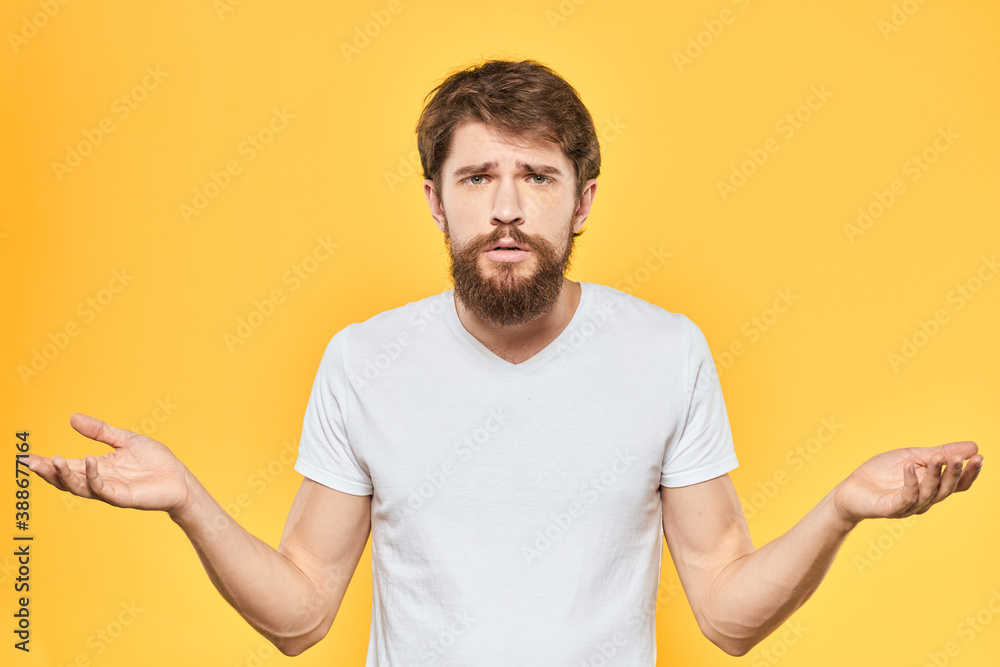 Bearded man emotions gestures with hands facial expression white t-shirt yellow background Bearded man emotions gestures with hands facial expression white t-shirt yellow background