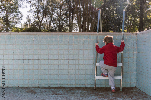 Obraz na płótnie Unrecognizable child climbing an empty pool ladder w salonie