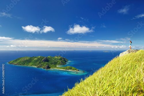 View of Kuata Island from Wayaseva Island with a hiker standing on a rock, Yasawas, Fiji