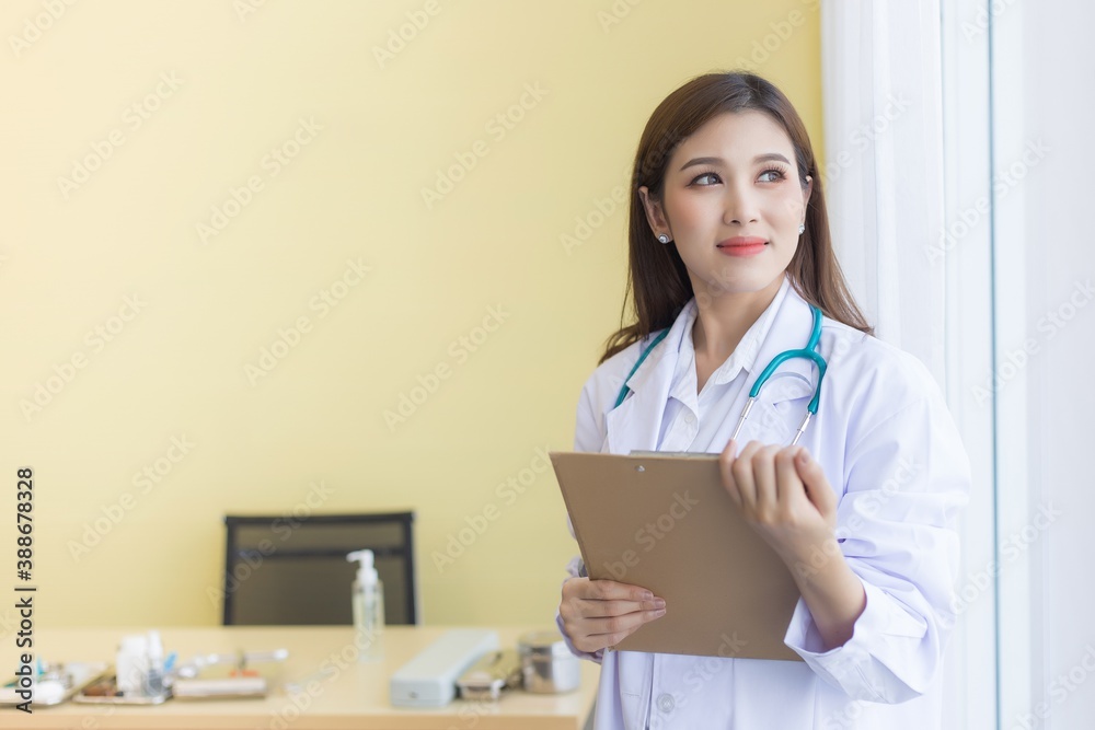 A beautiful Asian female doctor smiling, holding a clipboard and looking out of window. A beautiful Asian female doctor smiling, holding a clipboard and looking out of window.