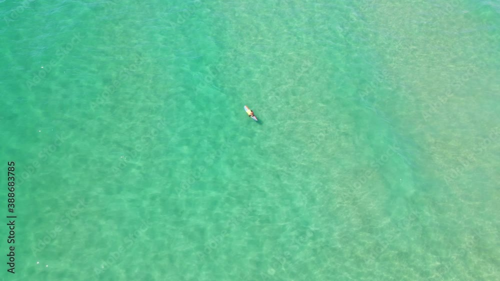 Surfer Sitting On Surfboard Floating On Blue Water - Palm Beach - Gold Coast, QLD, Australia. - aerial drone shot Surfer Sitting On Surfboard Floating On Blue Water - Palm Beach - Gold Coast, QLD, Australia. - aerial drone shot