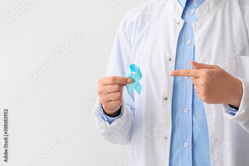Female doctor with awareness ribbon on light background, closeup. Diabetes concept