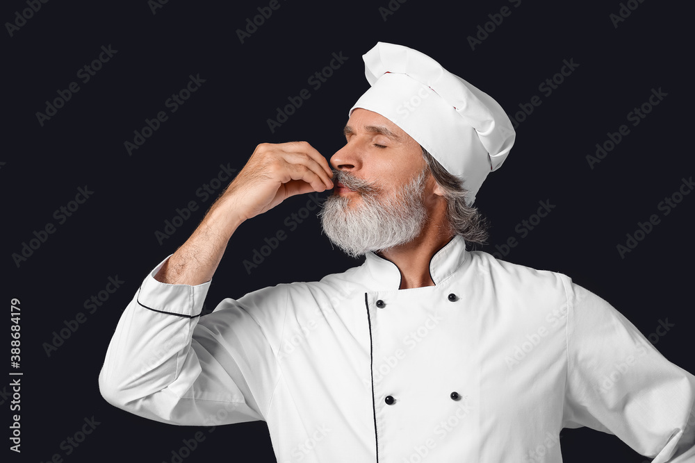 Mature male chef on dark background Mature male chef on dark background