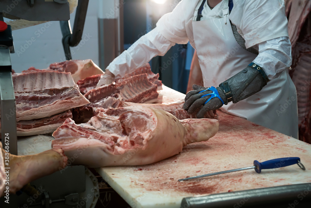 Meatman cuts freshly slaughtered meat of pork for sale and further processing as sausage