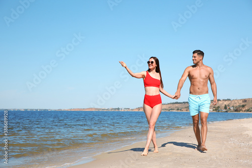 Woman in bikini and her boyfriend on beach, space for text. Happy couple © New Africa