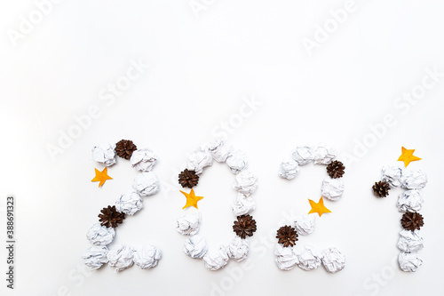 2021 figures from crumpled into a ball of white paper, pine cones and stars on a white background. New year concept