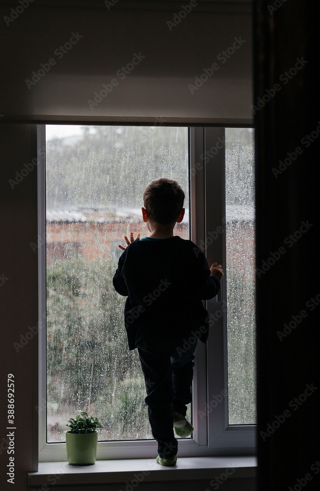 Fototapeta premium baby looks out the window, it's raining