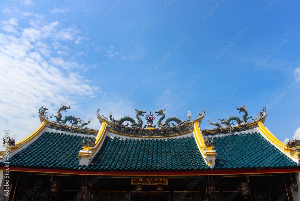 Naklejka premium A roof with dragon ornaments/statue of traditional Chinese temple in Semarang Indonesia. Blue sky as the background. 