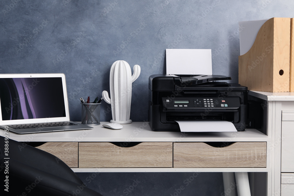 Modern printer and laptop on white table indoors