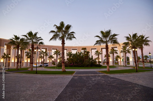 Palm trees and a colonnade with white columns in a small town square.