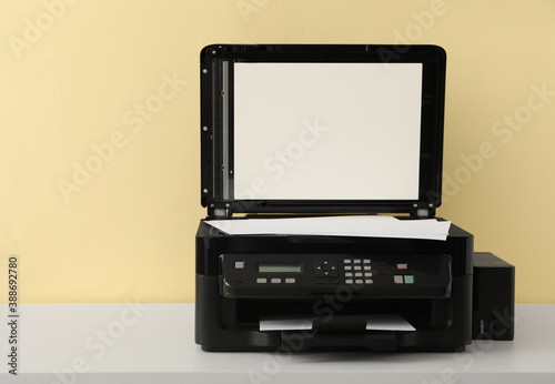 Modern printer with paper on white table
