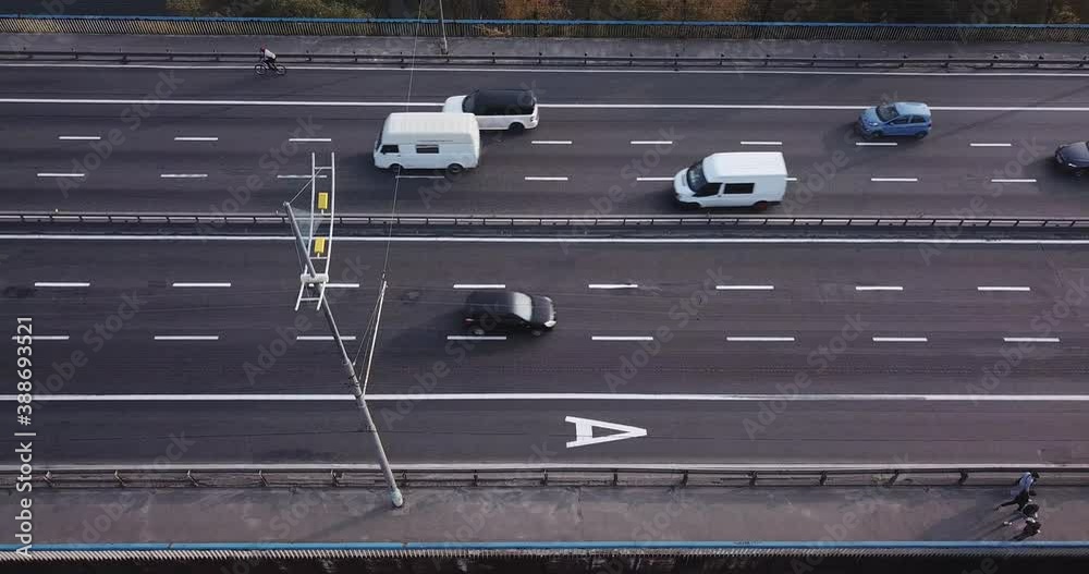View of the bridge carriageway from above at an angle, pedestrians and cyclists, at sunset.