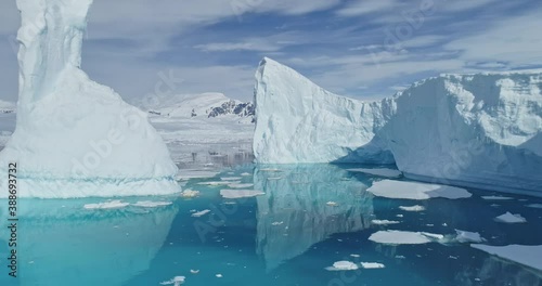 Tabular icebergs melt at turquoise ocean bay aerial. Huge high ice glacier at polar nature environment. Arctic winter landscape at global warming problem. Desert white land of snow and ice drone shot