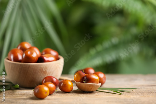 Fresh ripe oil palm fruits on wooden table. Space for text