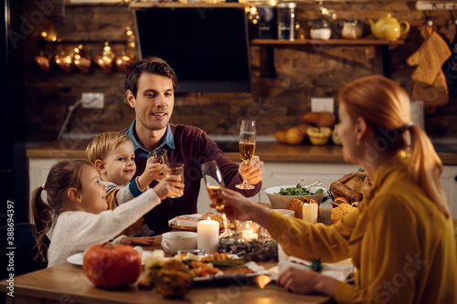 Happy family toasting during Thanksgiving meal in dining room.