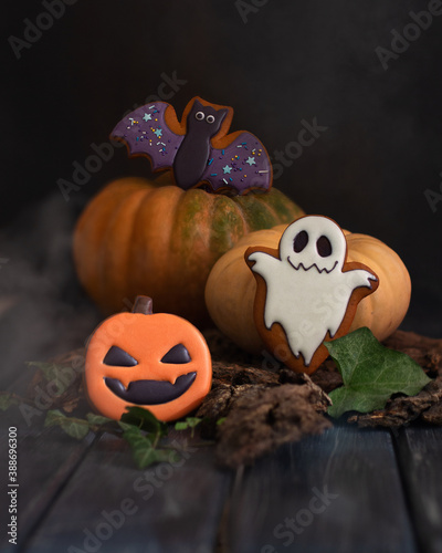 Gingerbread in the style of Halloween. Ghost, pumpkin, bat. The creative power of the smoke. Dark mood. Wooden background. copy space. Vertical orientation