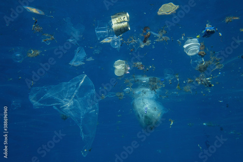 Plastic and other debris floats underwater in blue water. Plastic garbage polluting seas and ocean