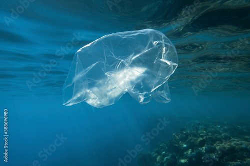 Used transparent plastic bag slowly drifting underwater over coral reef in the sun lights. Plastic debris underwater. Plastic garbage environmental pollution problem