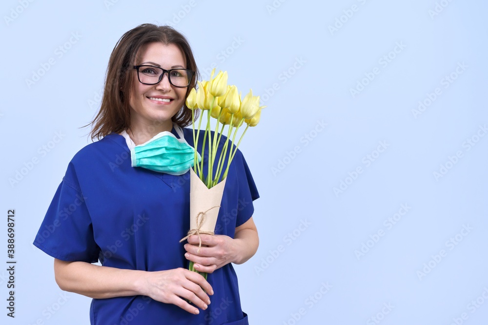 Smiling mature woman doctor nurse with bouquet of flowers, medical worker day, copy space Smiling mature woman doctor nurse with bouquet of flowers, medical worker day, copy space