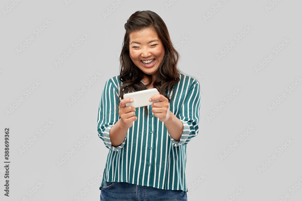 technology and people concept - happy asian woman using smartphone over grey background technology and people concept - happy asian woman using smartphone over grey background