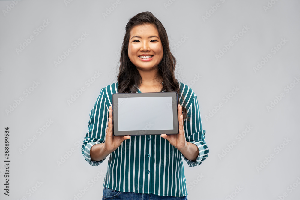technology and people concept - happy smiling asian woman using tablet computer over grey background technology and people concept - happy smiling asian woman using tablet computer over grey background