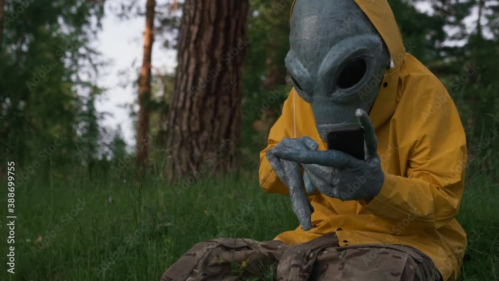 alien in yellow suit in forest talking on the phone, UFO concept, space, alien. alien in yellow suit in forest talking on the phone, UFO concept, space, alien.