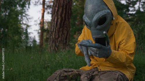 alien in yellow suit in forest talking on the phone, UFO concept, space, alien.