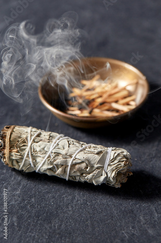 occult science and supernatural concept - white sage and cup with smoking matches photo