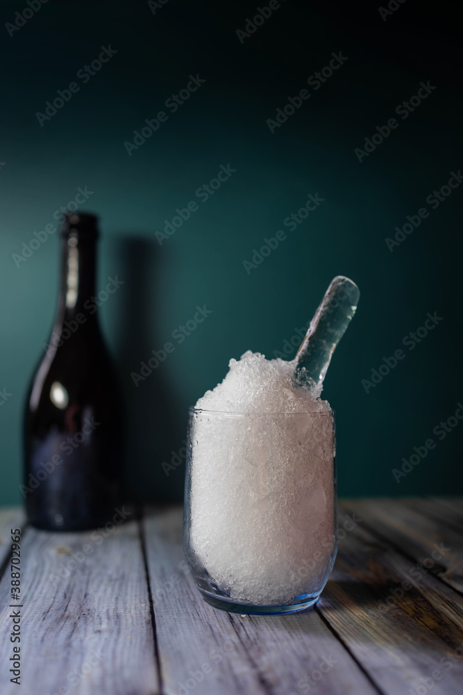 crystal glass with very fine crushed ice on wooden table