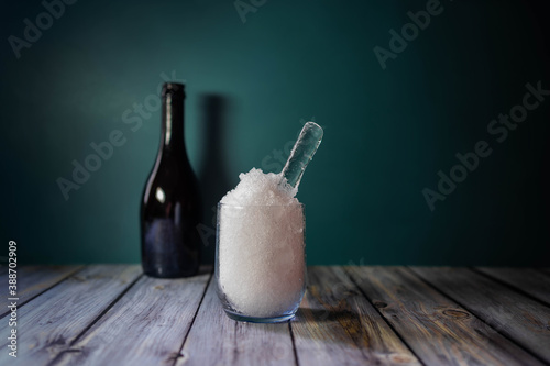 crystal glass with very fine crushed ice on wooden table