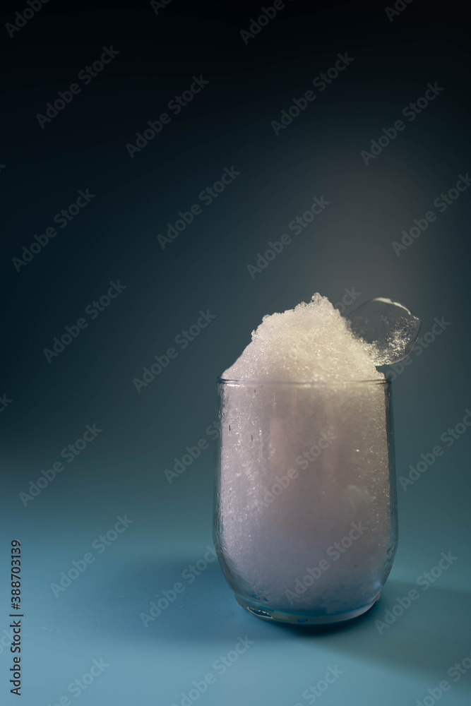 crystal glass with very fine crushed ice on blue background