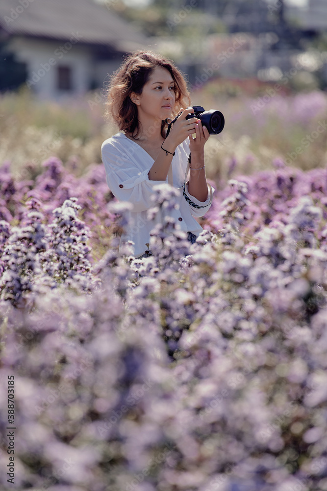 young cute woman professional photographer on a flower field in summer