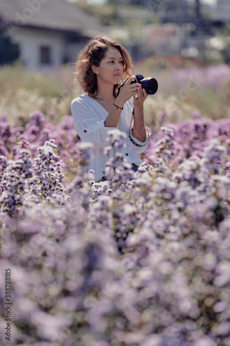 Obraz na płótnie young cute woman professional photographer on a flower field in summer w salonie