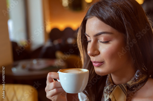 Beautiful young woman with closed eyes holding cup of coffee