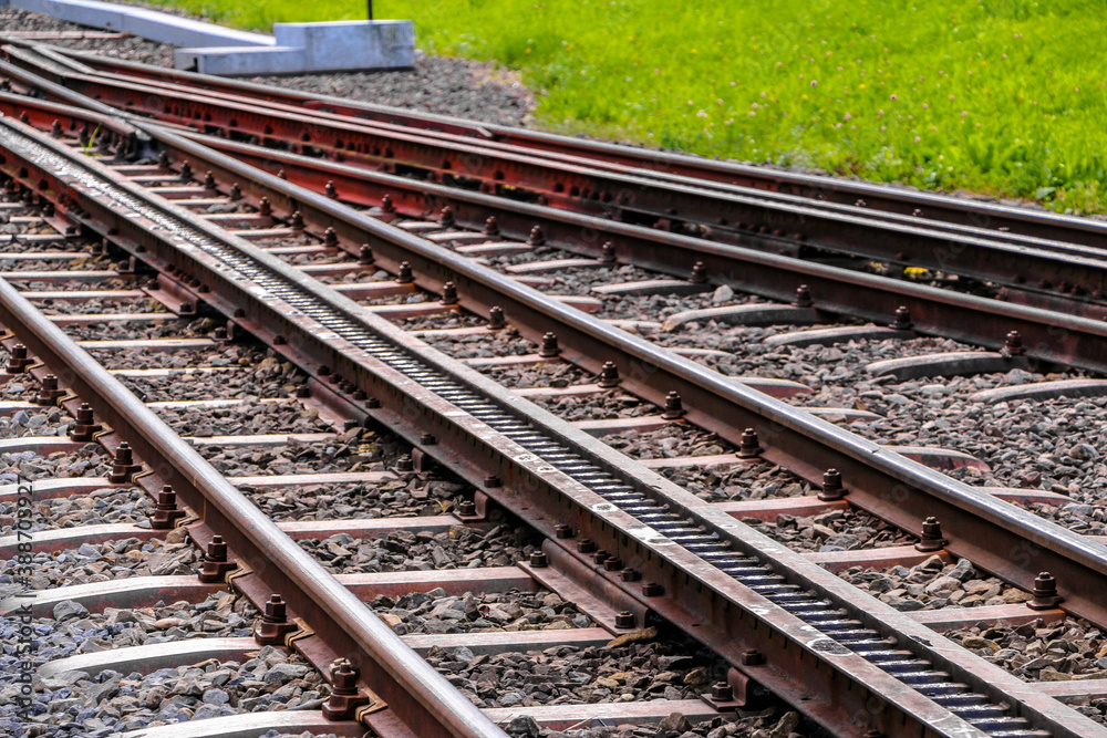 Paralell railroad tracks with green field next to it