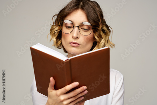 Business woman with notepad and glasses on a light background hairstyle success emotions © SHOTPRIME STUDIO
