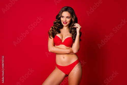 Photo of attractive beautiful curly lady advert underwear novelty sensual slim fit body bright pomade look empty space wear brassiere panties bikini isolated red vibrant color background