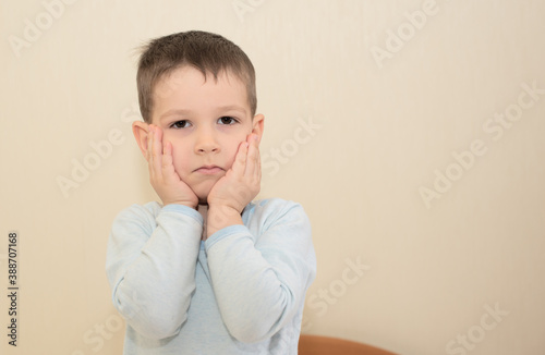 Upset, offended toddler boy with his hands touching a face. Concept of childhood. Copy space for your text.