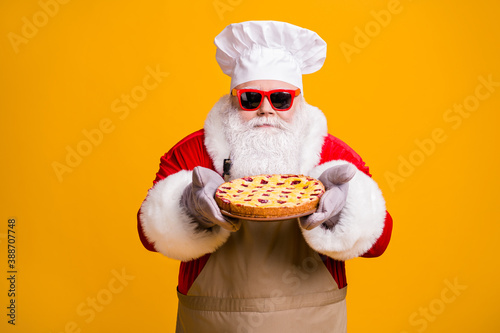 Photo of excited dreamy santa chef headwear grandpa grey white beard hold fresh sweet pie jam yummy flavor wear x-mas costume gloves sun specs cap apron isolated yellow color background