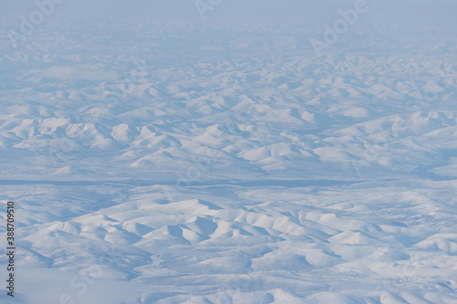Aerial view of snow-capped mountains. Winter snowy mountain landscape. Icheghem Range, Kolyma Mountains. Koryak Okrug (Koryakia), Kamchatka Krai, Siberia, Far East of Russia. Great for backgrounds.