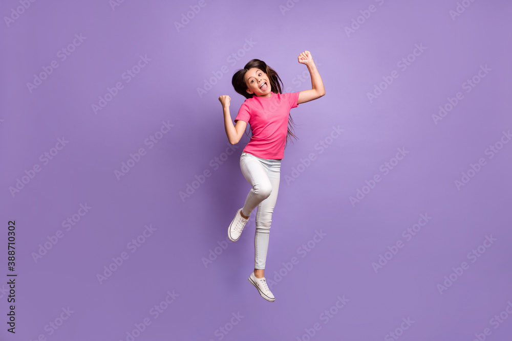 Full length body size photo of jumping high pretty schoolgirl with long brunette hair celebrating win cheering shouting loudly isolated on purple color background